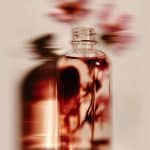 Flacon de sérum floral aux pétales roses en arrière-plan dans une ambiance lumineuse et sensorielle, identité visuelle studio de branding beauté et bien-être à Lyon